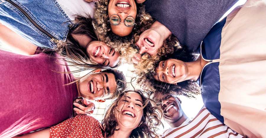 A diverse group of joyful family members standing in a circle and looking down at the camera with big smiles, showcasing successful family reunification.
