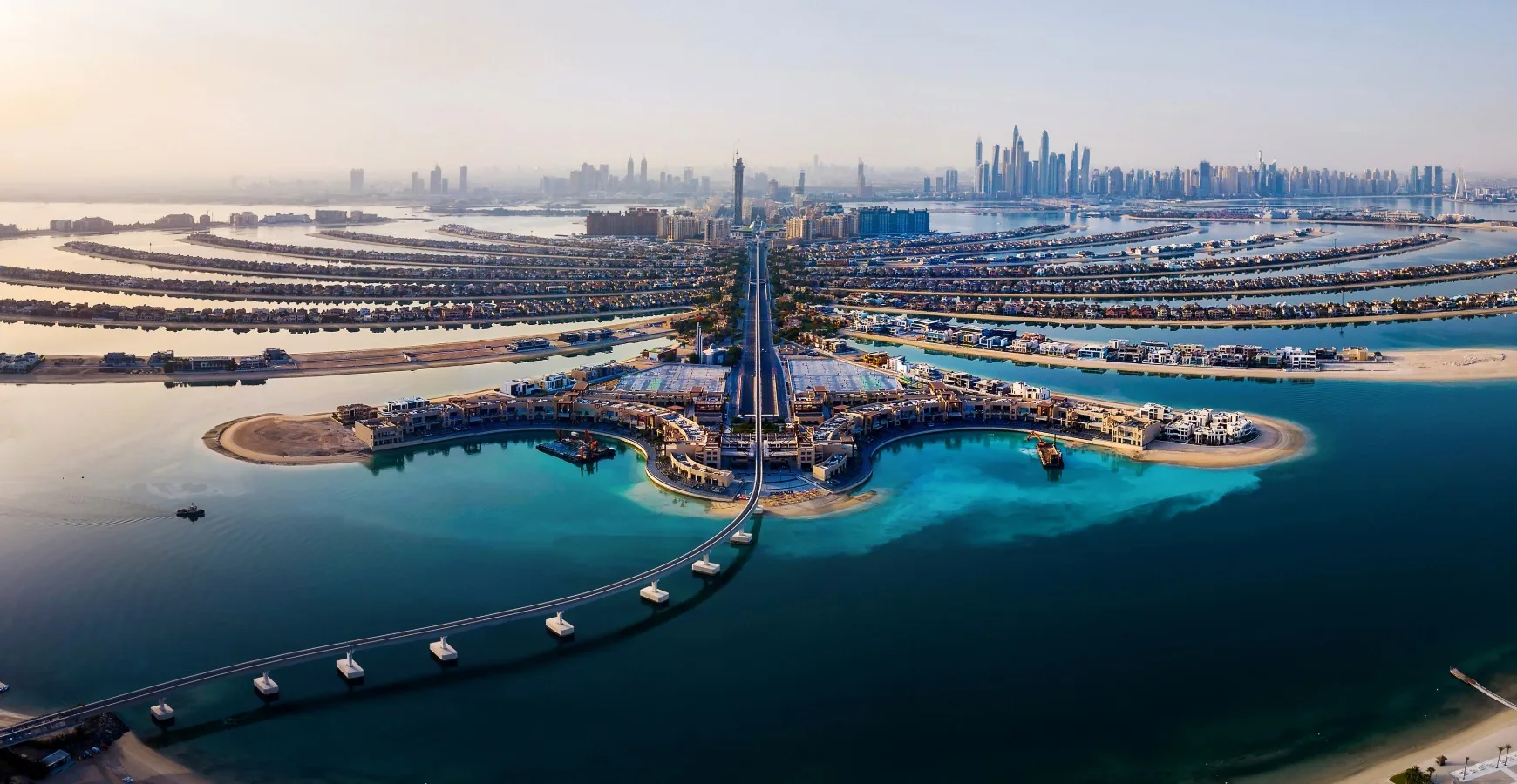 An aerial view of a massive man-made island development with luxury coastal residences and a long bridge stretching into deep blue ocean water, highlighting Mauritius offshore investment opportunities.