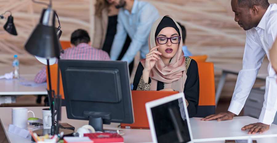 A diverse corporate team collaborating at a modern office desk, illustrating company formation and Qatar business setup services.